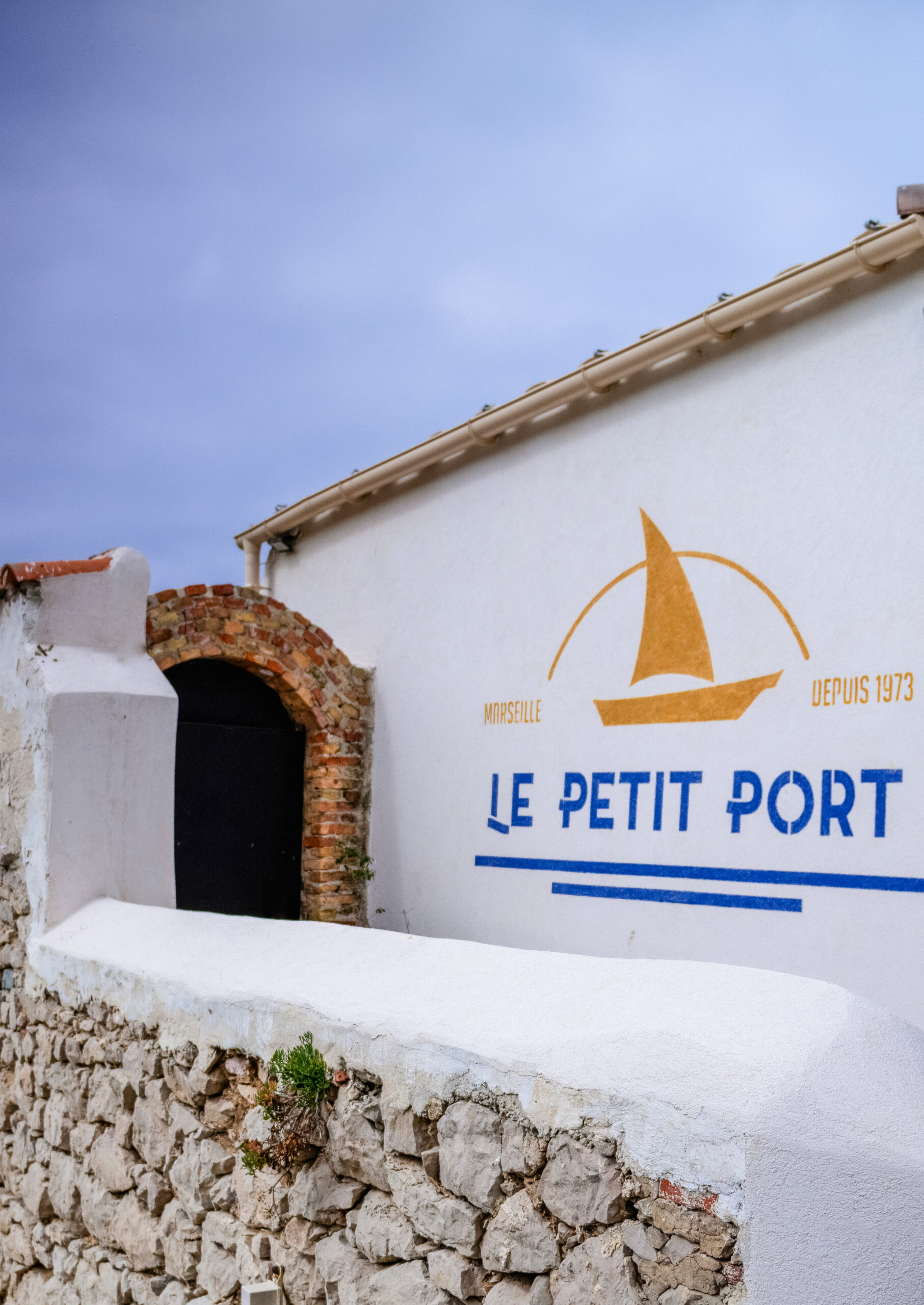 Façade du restaurant Le Petit Port aux Goudes Marseille avec logo peint sur le mur blanc